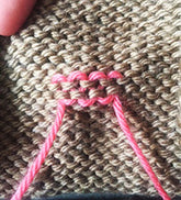 tan knitted fabric with pink yarn ends woven in