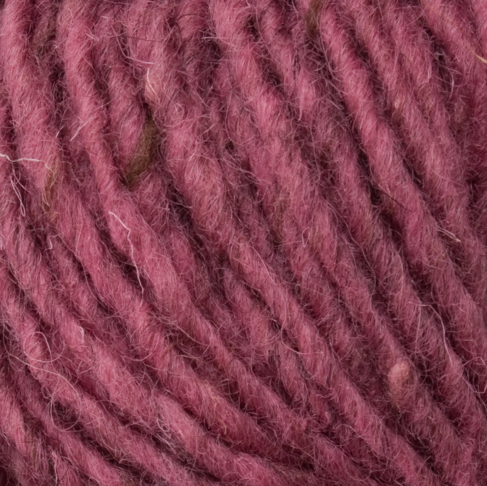 Close-up image of a textured ball of Halcyon Geo Rug Wool in a rich maroon color, showing its fibers and twists in detail. The yarn appears soft and woolly, suggesting it is suitable for knitting or crocheting projects, much like the quality you'd expect from Caledonian Dye Works.