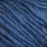 A close-up view of Caledonian Dye Works' Halcyon Geo Rug Wool in blue reveals its soft, fuzzy texture and intricately twisted strands. The consistent color features subtle variations in the fibers, giving it a slightly heathered appearance. This tightly spun yarn showcases fine detail and embodies a cozy feel.