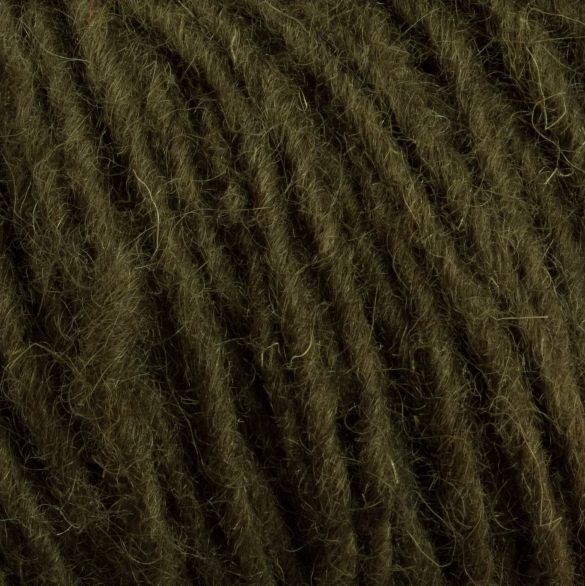 Close-up image of dark green Halcyon Geo Rug Wool by Caledonian Dye Works. The fibers are tightly twisted, showcasing the texture and slight fuzziness of the material. The image focuses on the intricate details and natural appearance of this premium yarn.