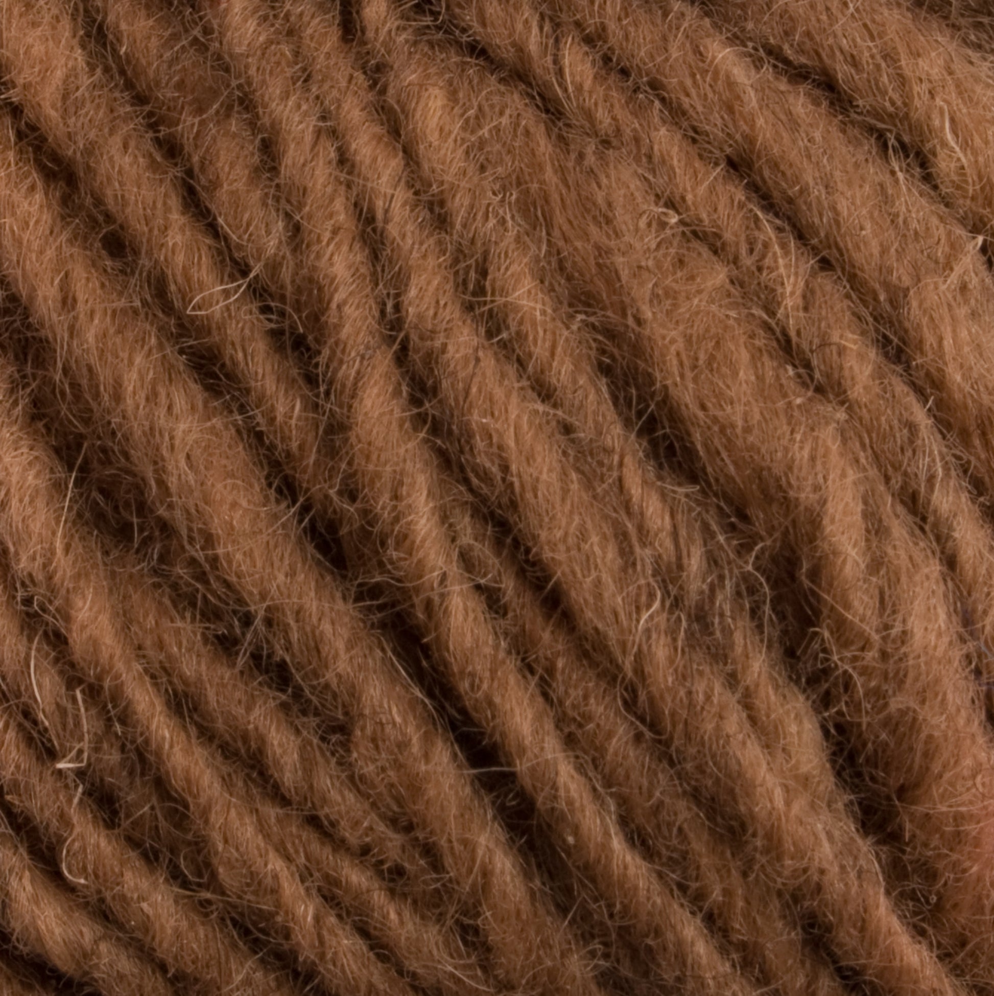 Close-up view of a section of warm, soft brown Halcyon Geo Rug Wool by Caledonian Dye Works. The yarn strands are tightly twisted together, showcasing a slightly fuzzy texture. The color is uniform and rich, emphasizing the fiber's natural appeal.