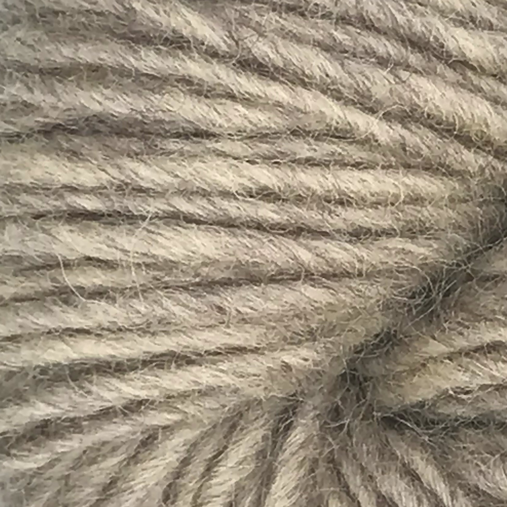 Close-up image of gray Halcyon Geo Rug Wool from Caledonian Dye Works, showcasing its soft texture and twisted strands. The yarn exhibits a natural, slightly variegated look with subtle color variations.