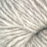 Close-up image of a ball of light grey Halcyon Geo Rug Wool from Caledonian Dye Works, showcasing the tightly woven and soft texture of the fibers.