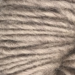 Close-up of a skein of Halcyon Geo Rug Wool by Caledonian Dye Works in a soft, light gray shade with a slightly fuzzy texture. The strands are thick and loosely twisted, creating a cozy look reminiscent of traditional rug wool. The image highlights the intricate details and fibers of the yarn.