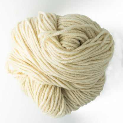 A skein of Lemieux Halcyon Yarn 4-ply Rug Wool, weighing 16 oz and in an off-white hue, is coiled loosely against a plain white background. The thick, soft yarn appears chunky and is ideal for rug hookers as well as suitable for knitting or crocheting.