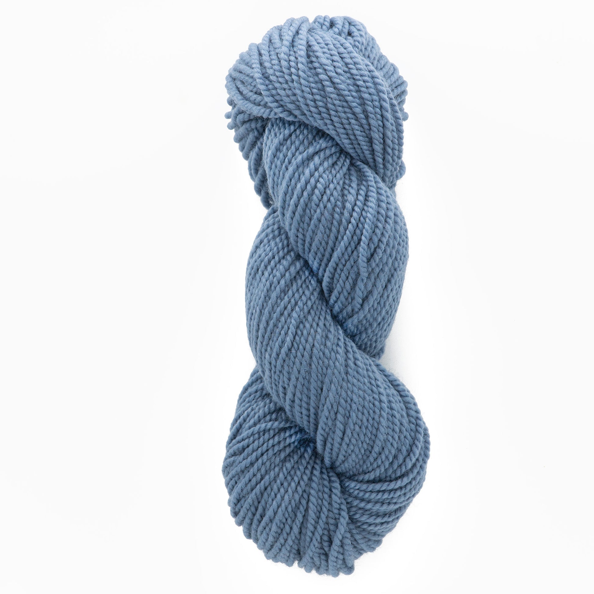 A neatly twisted skein of Norumbega, a chunky blue yarn made entirely from U.S. wool by Caledonian Dye Works, sits against a white background. The Aran weight yarn appears soft and suitable for knitting or crocheting projects.