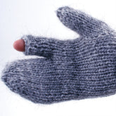 A close-up of a gray knitted mitten, crafted with bulky yarn from Halcyon Yarn's Guard's Gauntlet pattern, reveals the tip of the thumb exposed through a small hole. The background is plain and light in color, highlighting the mitten's texture. Perfect inspiration for your next Knit-a-Long project!