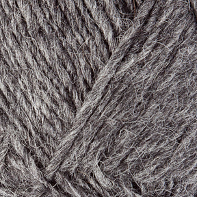 Close-up of grey Lopi Alafoss Icelandic Wool Yarn by Berroco, Inc., showcasing its coarse texture and intertwined fibers. The yarn appears thick and made of natural material, ideal for knitting or crocheting projects like felted mittens or Icelandic pullovers. The color offers varying shades of grey, adding depth to the texture.