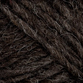 Close-up of dark brown Lopi Alafoss Icelandic Wool Yarn from Berroco, Inc., with lighter, off-white fibers interwoven. The texture appears thick and slightly rough, suitable for knitting or crochet projects like cozy felted mittens. The image highlights the intricate details and variations in the yarn's fibers.