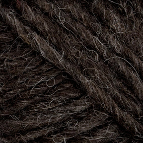 Close-up of dark brown Lopi Alafoss Icelandic Wool Yarn from Berroco, Inc., with lighter, off-white fibers interwoven. The texture appears thick and slightly rough, suitable for knitting or crochet projects like cozy felted mittens. The image highlights the intricate details and variations in the yarn's fibers.