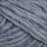 The close-up view of the soft, chunky light blue yarn reveals it to be Lopi Alafoss Icelandic Wool Yarn by Berroco, Inc. The thick strands are tightly intertwined, showcasing a fibrous and slightly fuzzy texture, perfect for crafting traditional Icelandic pullovers.