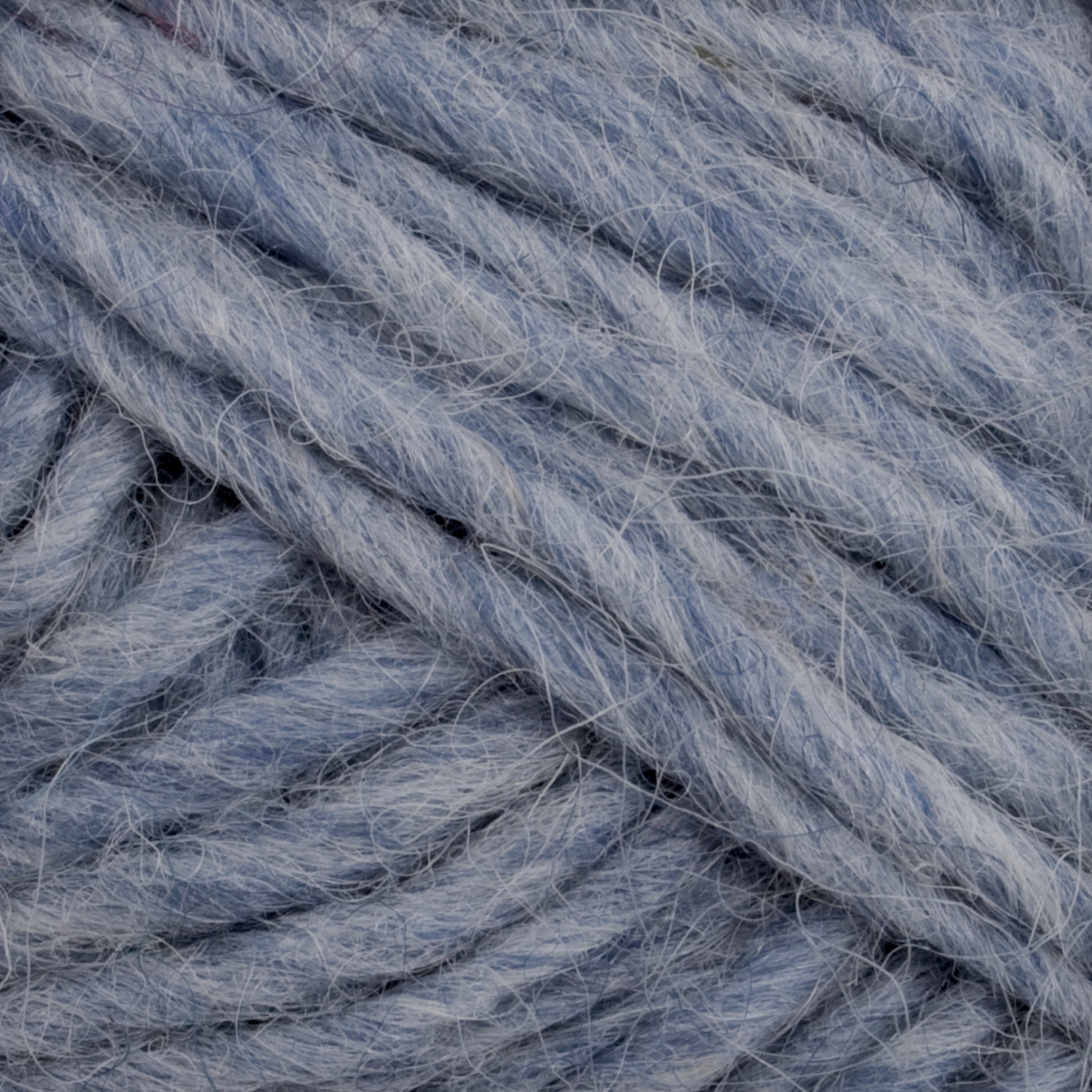 The close-up view of the soft, chunky light blue yarn reveals it to be Lopi Alafoss Icelandic Wool Yarn by Berroco, Inc. The thick strands are tightly intertwined, showcasing a fibrous and slightly fuzzy texture, perfect for crafting traditional Icelandic pullovers.