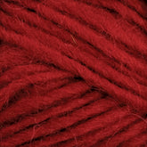 Close-up of deep red Lopi Alafoss Icelandic Wool Yarn by Berroco, Inc. The texture appears soft and slightly fluffy with individual strands tightly wound together, ideal for crafting Icelandic pullovers. Threads are neatly positioned, filling the entire frame.