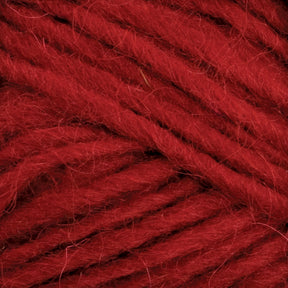 Close-up of deep red Lopi Alafoss Icelandic Wool Yarn by Berroco, Inc. The texture appears soft and slightly fluffy with individual strands tightly wound together, ideal for crafting Icelandic pullovers. Threads are neatly positioned, filling the entire frame.