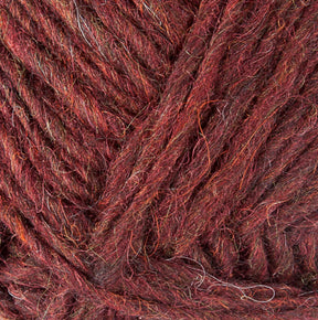 Close-up of a ball of Berroco, Inc.'s Lopi Alafoss Icelandic Wool Yarn in deep burgundy with subtle strands of brown and orange interwoven. The texture is soft, with a slightly irregular and fibrous appearance, showcasing a rich, warm color blend suitable for knitting felted mittens or Icelandic pullovers.