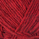 Close-up of Berroco, Inc.'s Lopi Alafoss Icelandic Wool Yarn, showing the texture of the fibers and strands. The yarn is tightly spun and appears soft, with various shades of red giving it a rich, vibrant look—perfect for creating Icelandic pullovers or felted mittens.