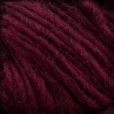 Close-up of Lopi Alafoss Icelandic Wool Yarn by Berroco, Inc., showcasing its deep burgundy hue and thick, fuzzy texture with intricately intertwined fibers. The rich color and soft appearance suggest it would be cozy for knitting or crocheting projects, making it perfect for crafting felted mittens or classic Icelandic pullovers.