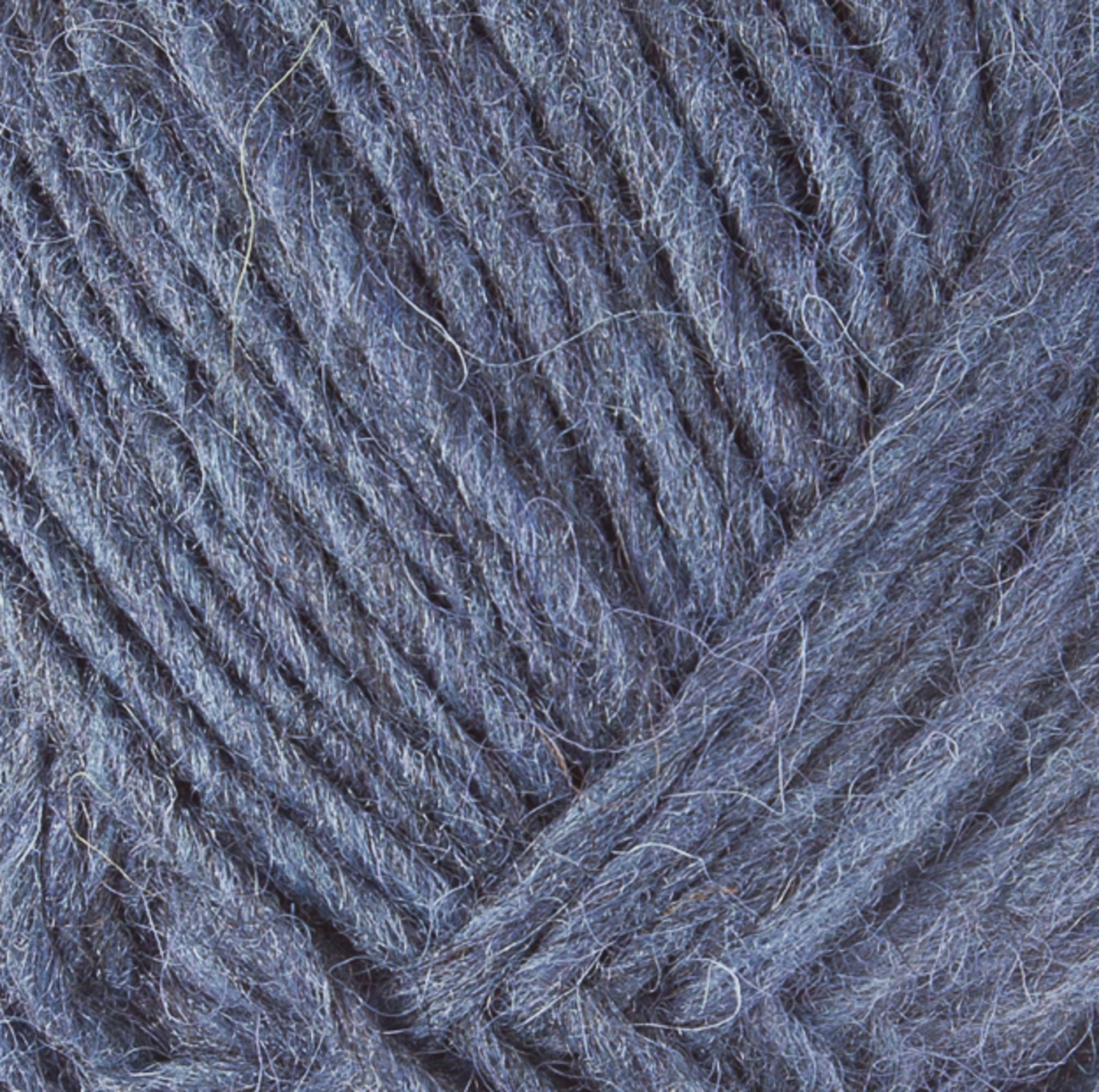 A close-up image of blue Lopi Alafoss Icelandic Wool Yarn by Berroco, Inc., showcasing the sharp details of the fibers and strands tightly wound together. The texture appears soft and slightly fuzzy, reminiscent of traditional Icelandic pullovers, with some visible loose fibers.