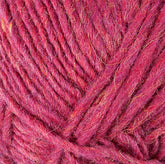 A close-up image of Berroco, Inc.'s Lopi Alafoss Icelandic Wool Yarn in red and pink, highlighting the texture and intricate details of the interwoven fibers. The yarn appears soft and slightly fuzzy, reminiscent of that used in traditional Icelandic pullovers, with various shades and hues giving it depth.