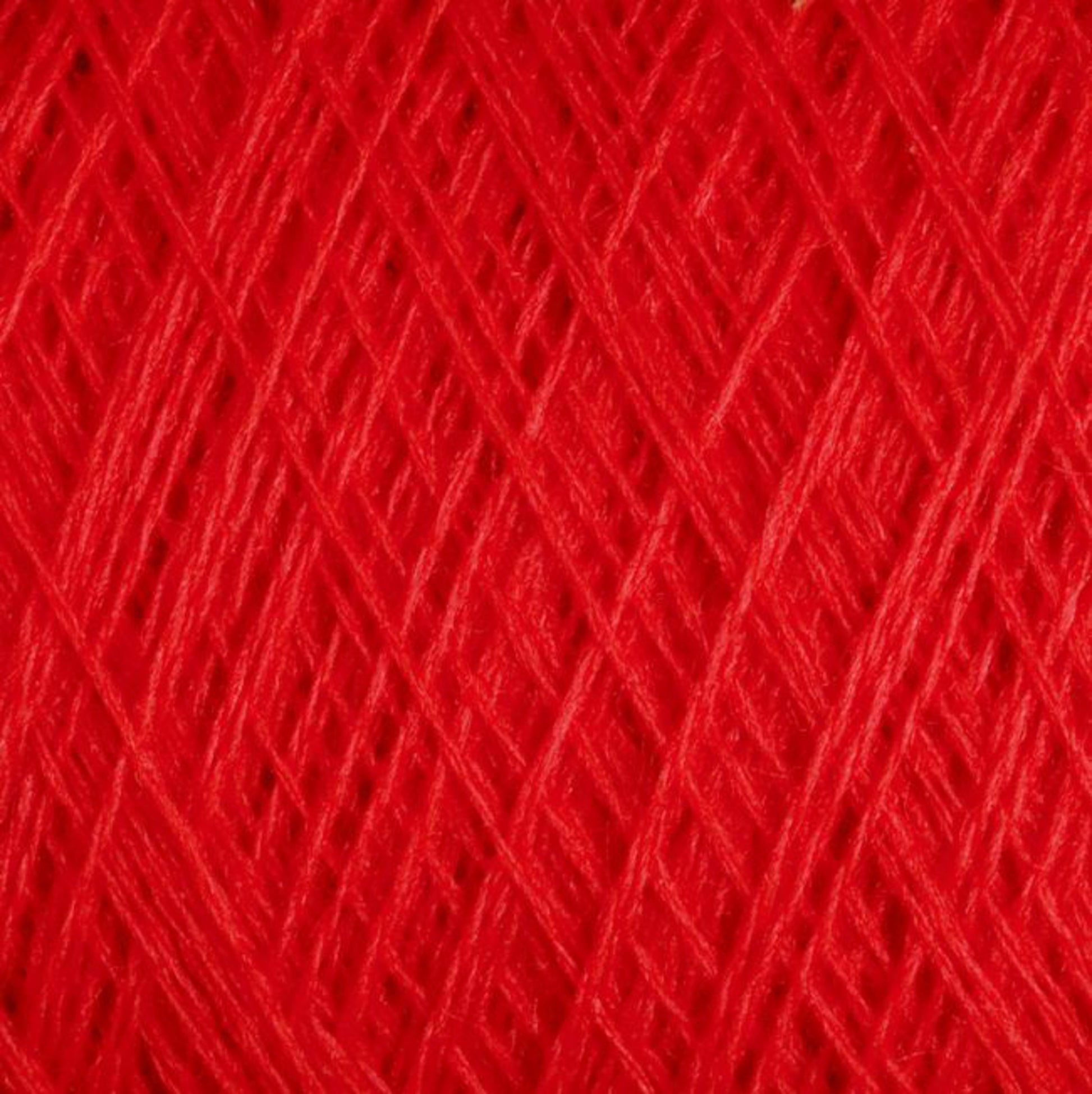 A close-up view of the vibrant red JaggerSpun Maine Line 3/8 Yarn on a large cone by Jagger Brothers, Inc. The texture is visible, showing intricate, crisscrossing threads of worsted spun yarns tightly wound together. The image highlights the rich color and the fine details of the soft medium-grade wool fibers.
