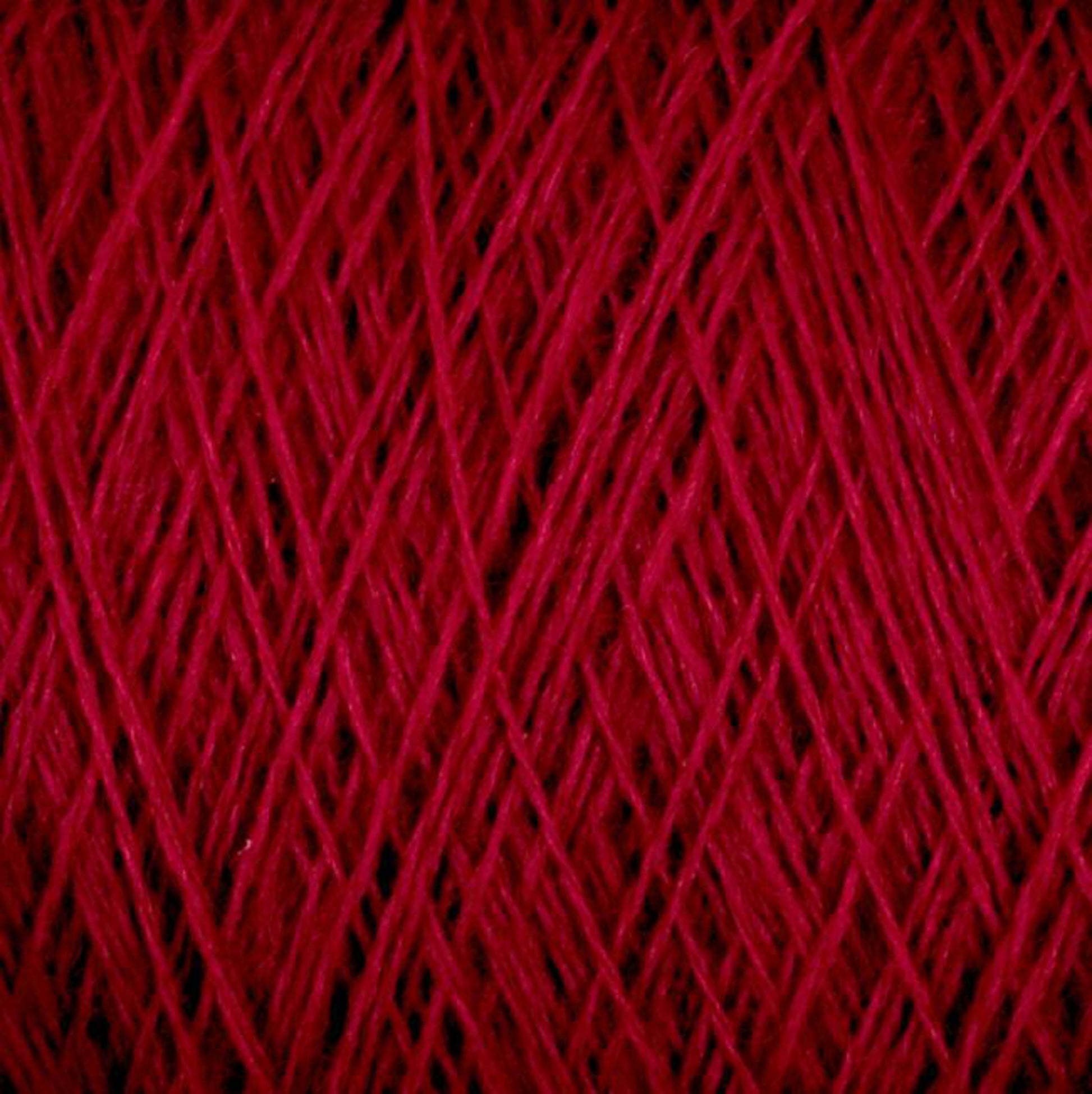 A close-up view of a spool of JaggerSpun Maine Line 3/8 Yarn | Mini-cone by Jagger Brothers, Inc. showcases the rich, red threads tightly wound in crisscross patterns, creating a textured surface. The vivid red color is evenly distributed throughout the worsted spun yarns.