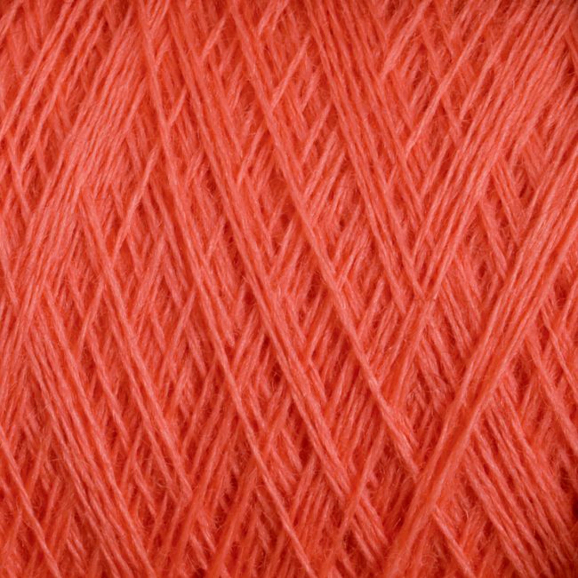 Close-up image of a large spool of bright orange JaggerSpun Maine Line 3/8 Yarn from Jagger Brothers, Inc., highlighting the tightly wound and thin fibers. The texture appears soft and smooth, ideal for knitting or crocheting projects. This product features vibrant color consistent throughout the image.