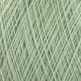 Close-up of the pale green JaggerSpun Maine Line 3/8 Yarn | Mini-cone by Jagger Brothers, Inc., neatly wound into a ball. The individual strands of the soft, fuzzy thread are visible, showcasing a delicate and intricate texture. The overall appearance is light and airy, emphasizing the material's softness and consistency.