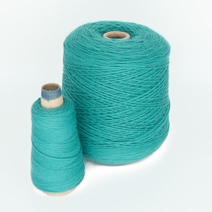 Two spools of Jagger Brothers, Inc. JaggerSpun Maine Line 3/8 Yarn in turquoise are displayed against a plain, light grey background. The larger spool is full and cylindrical, while the smaller mini-cone is similarly shaped but contains less yarn and has a visible cardboard core at the top.