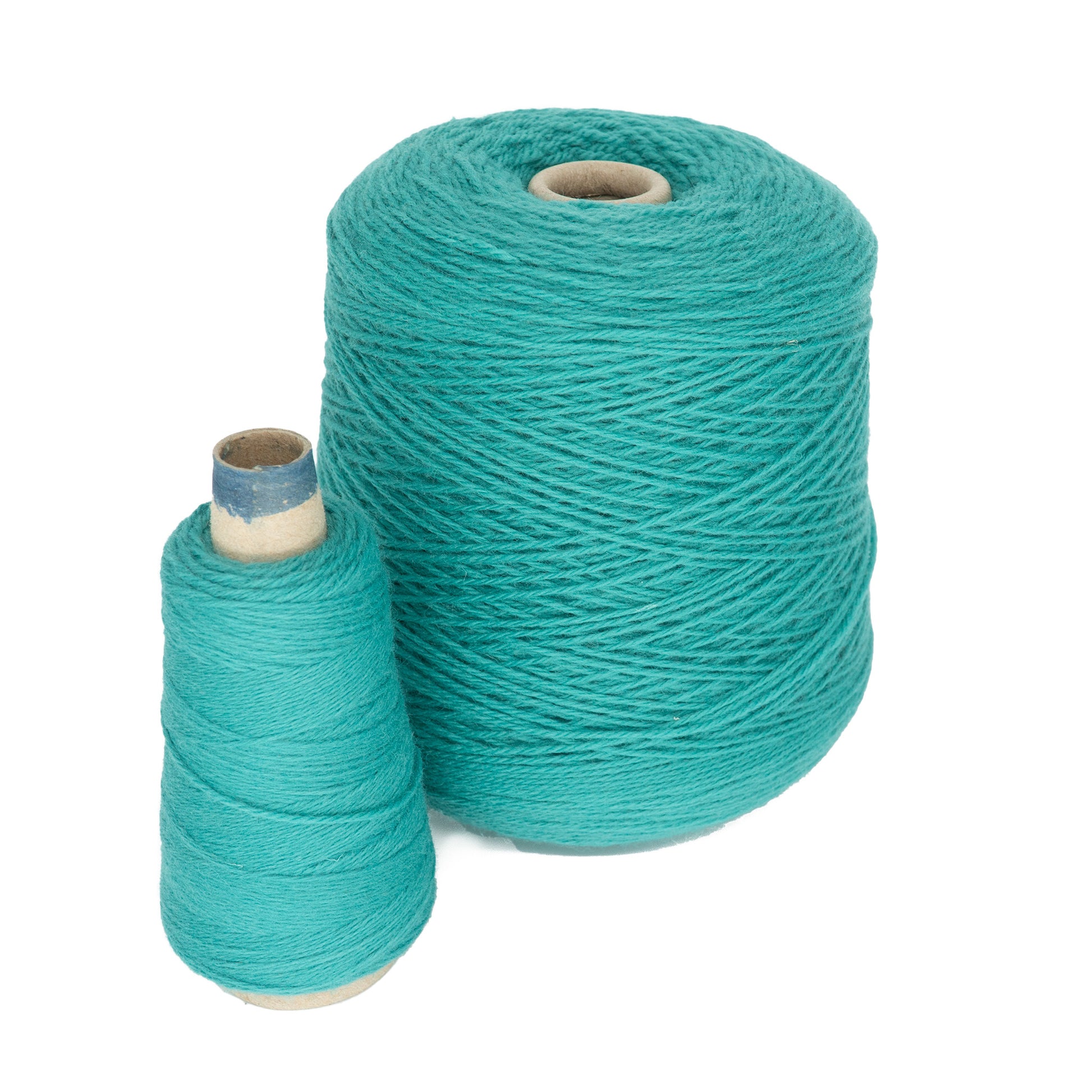 A mini-cone of teal JaggerSpun Maine Line 3/8 Yarn by Jagger Brothers, Inc. is positioned to the left against a white background, with a larger spool on the right. Both worsted spun yarns have a tightly wound texture and are set upright.