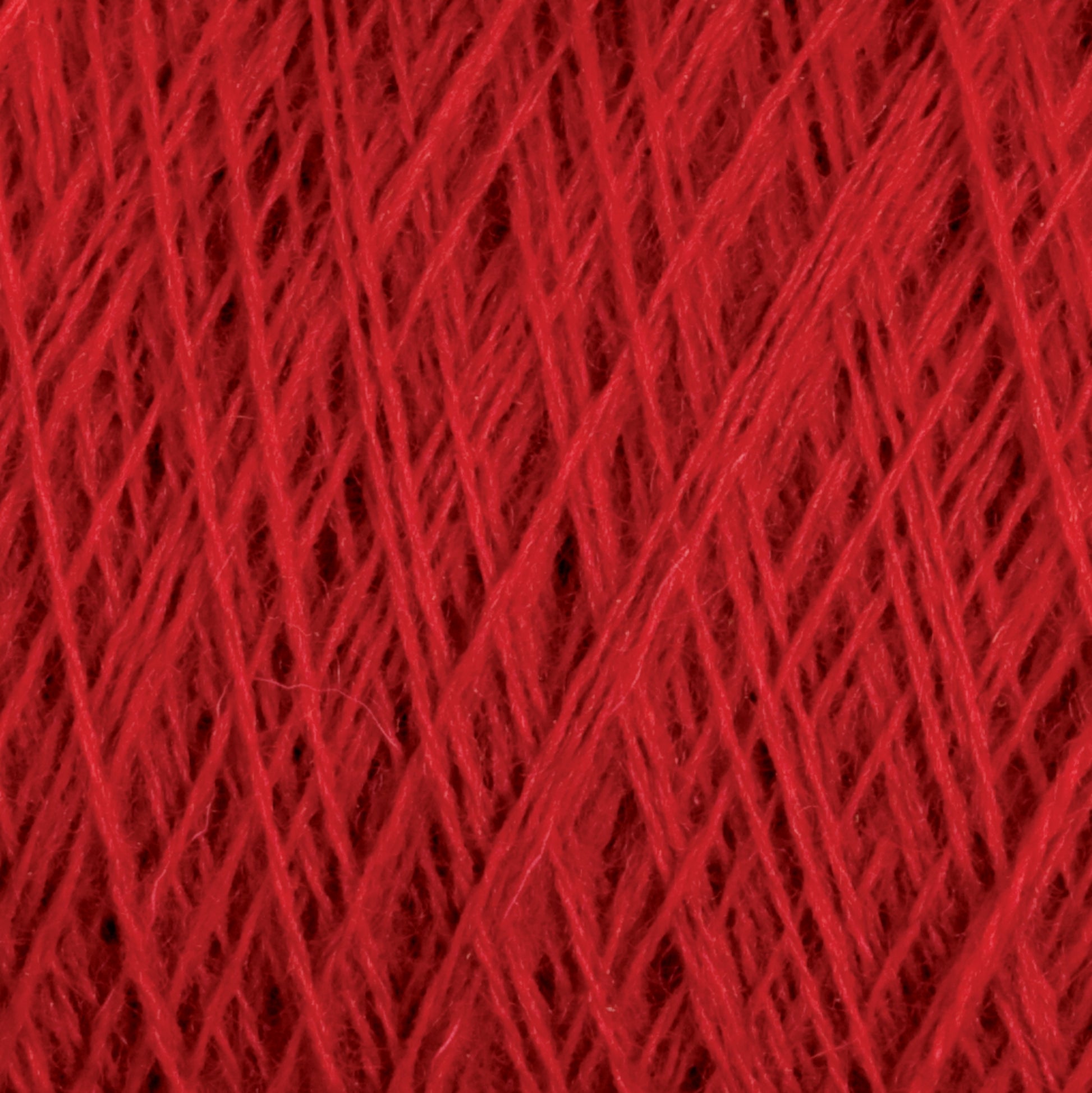 Close-up of a ball of red JaggerSpun Maine Line 2/8 Yarn from Jagger Brothers, Inc., showing a detailed and intricate pattern of tightly wound strands forming a dense, textured surface. The worsted spun yarn's individual fibers are visible, creating a rich and vibrant tapestry of crimson hues perfect for knitting or weaving projects.