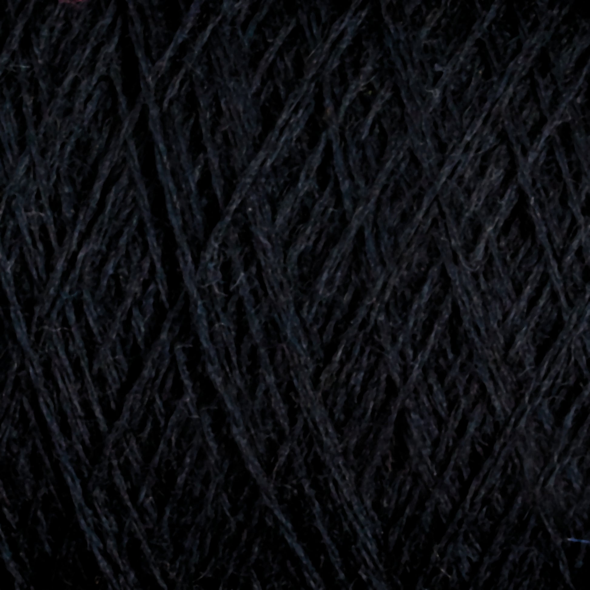 A close-up image of JaggerSpun Maine Line 2/8 Yarn | Mini-cone by Jagger Brothers, Inc. The worsted spun yarn is tightly wound, showcasing its fibrous texture and intricate overlapping strands. The detailed view highlights the thickness and subtle variations in the fiber, making it perfect for weaving or knitting projects.