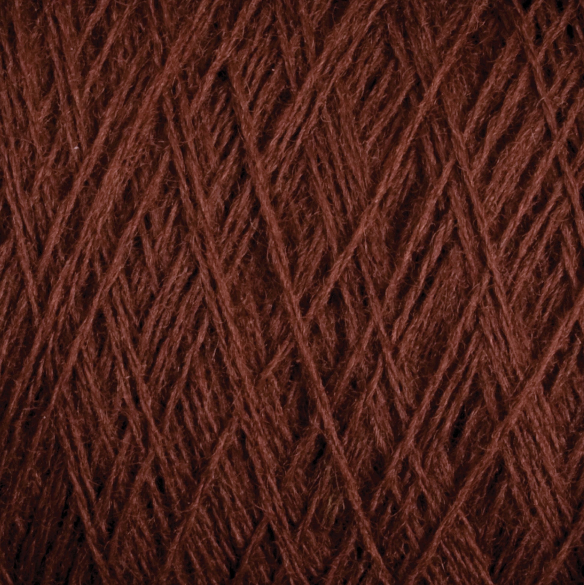 Close-up view of JaggerSpun Maine Line 2/8 Yarn in brown from Jagger Brothers, Inc., showcasing the intricate interwoven fibers and textures. The strands overlap in a detailed pattern, highlighting the natural and rich color of this worsted spun yarn, perfect for weaving or knitting projects.