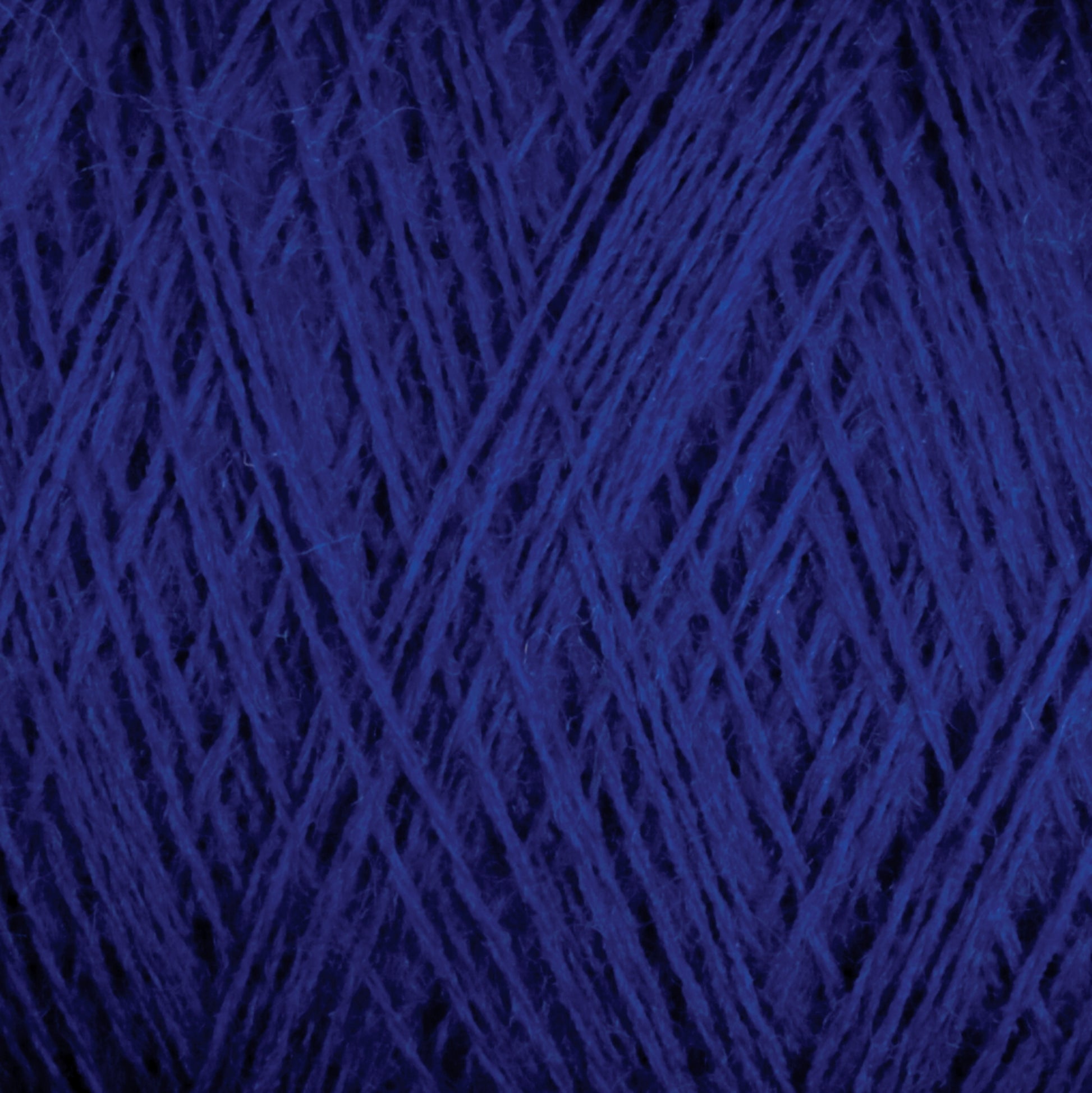 Close-up image of JaggerSpun Maine Line 2/8 Yarn | Mini-cone in blue by Jagger Brothers, Inc. The photo captures the intricate details of the tightly wound fibers, highlighting the texture and deep blue color of the yarn. The focus is on the crisscrossing strands, creating a pattern reminiscent of knitting throughout the image.