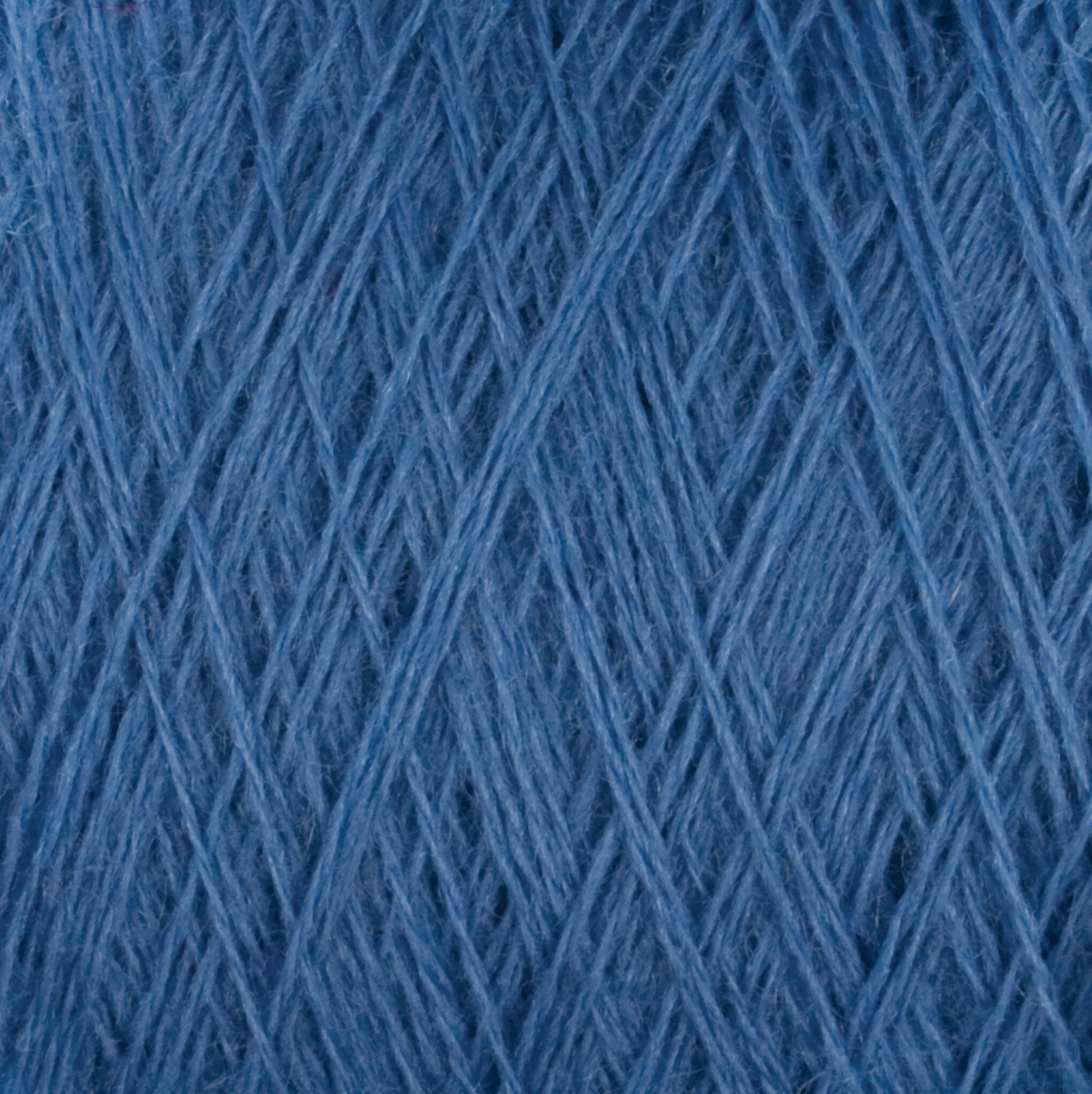 Close-up image of a ball of JaggerSpun Maine Line 2/8 Yarn mini-cone by Jagger Brothers, Inc. The strands are tightly wound and crisscross in various directions, creating an intricate pattern and texture, perfect for knitting.