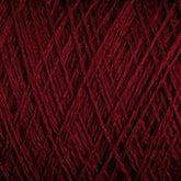 Close-up image of JaggerSpun Maine Line 2/8 Yarn by Jagger Brothers, Inc., wound tightly in a ball, showcasing the texture and intricate overlapping strands of burgundy-colored fiber. The rich color and uniform pattern highlight the yarn's softness and suitability for commercial and recreational knitters looking to craft beautiful projects.