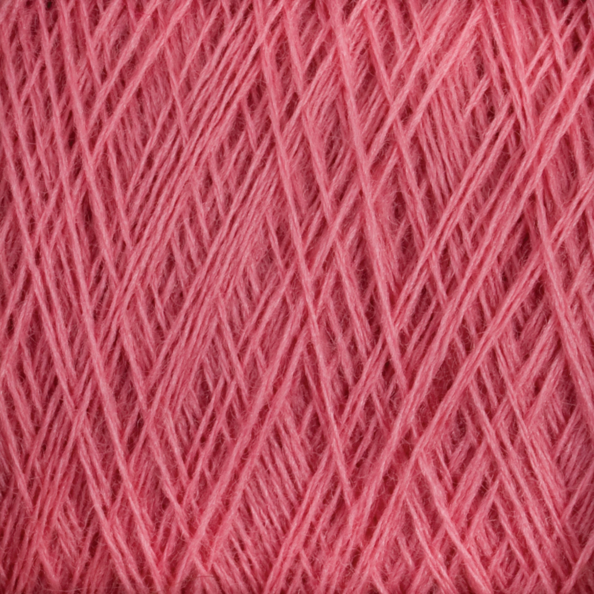 Close-up of light, pink JaggerSpun Maine Line 2/8 Yarn strands intricately wound and layered, forming a dense, crisscrossing pattern. The texture appears soft and fluffy, making it suitable for knitting or crochet projects. Bright lighting highlights the yarn's details and its vibrant color from Jagger Brothers, Inc.'s Mini-cone collection.