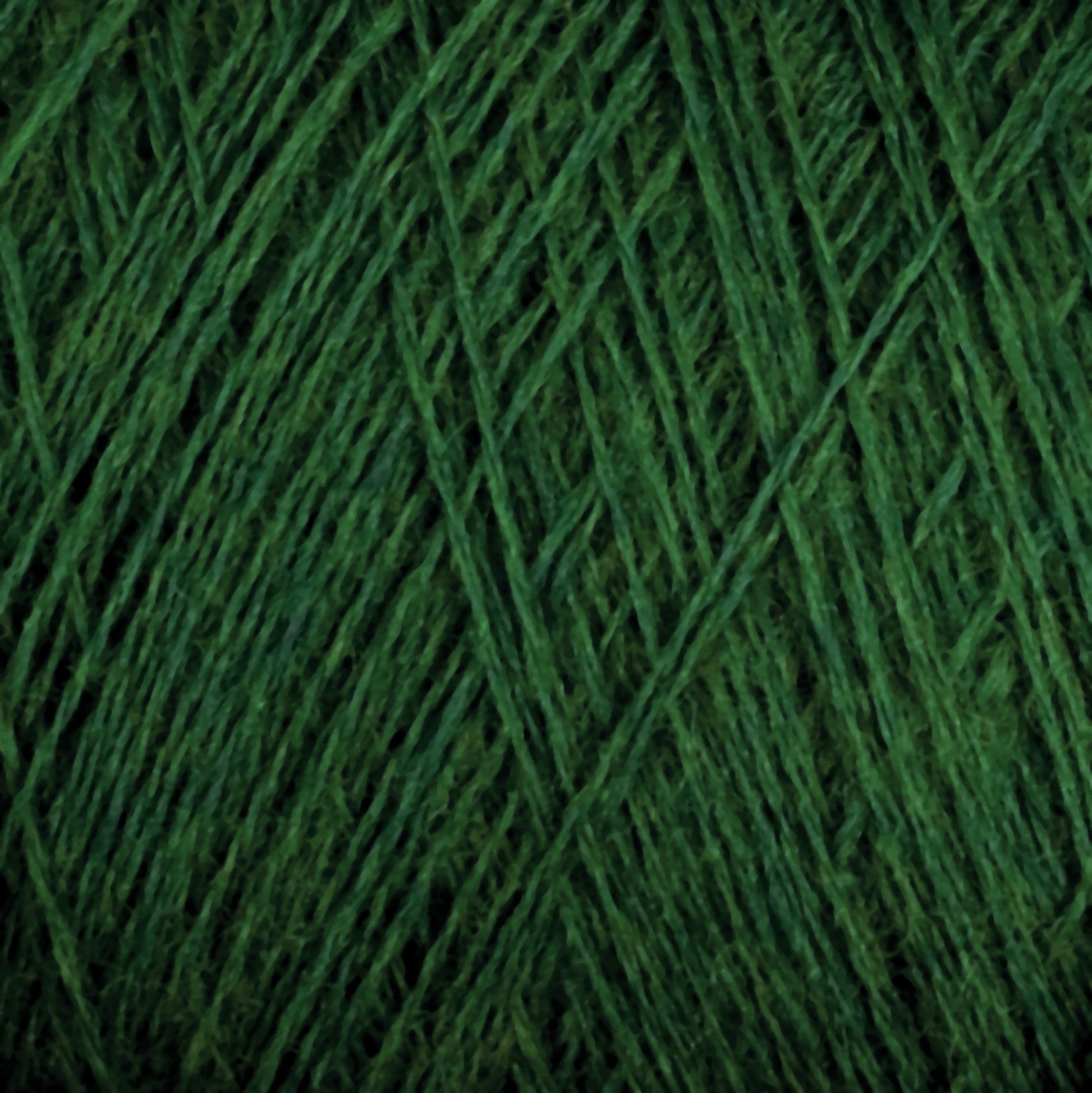 Close-up image of JaggerSpun Maine Line 2/8 Yarn | Mini-cone by Jagger Brothers, Inc., showcasing the dark green yarn. The worsted spun fibers are tightly wound, highlighting its soft and thick texture. Ideal for knitting or weaving, this yarn features a rich, forest green hue.