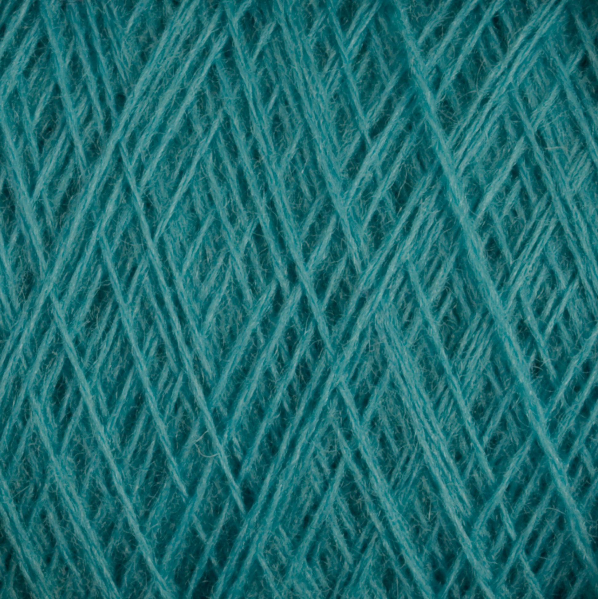 Close-up view of tightly woven, teal-colored JaggerSpun Maine Line 2/20 Yarn | Large Cone by Jagger Brothers, Inc., creating a textured and intertwined pattern. The image emphasizes the detailed fibers and crosshatching weave of the worsted spun yarns.