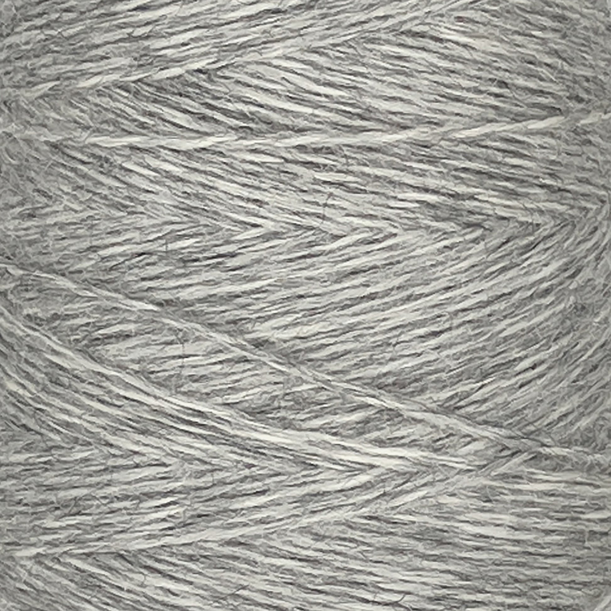 Close-up view of a spool of light gray Jagger Brothers, Inc. JaggerSpun Heather 2/8 yarn. The fingering gauge wool has a fine, slightly textured appearance, with fibers tightly wound together in a crisscross pattern around the large cone.