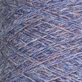 Close-up of a mini-cone of JaggerSpun Heather 2/8 yarn by Jagger Brothers, Inc., featuring a mix of purple, blue, and gray fibers. The texture is coarse and tightly wound, revealing intricate details of the interwoven strands. The softly blended colors create an overall muted pastel effect.