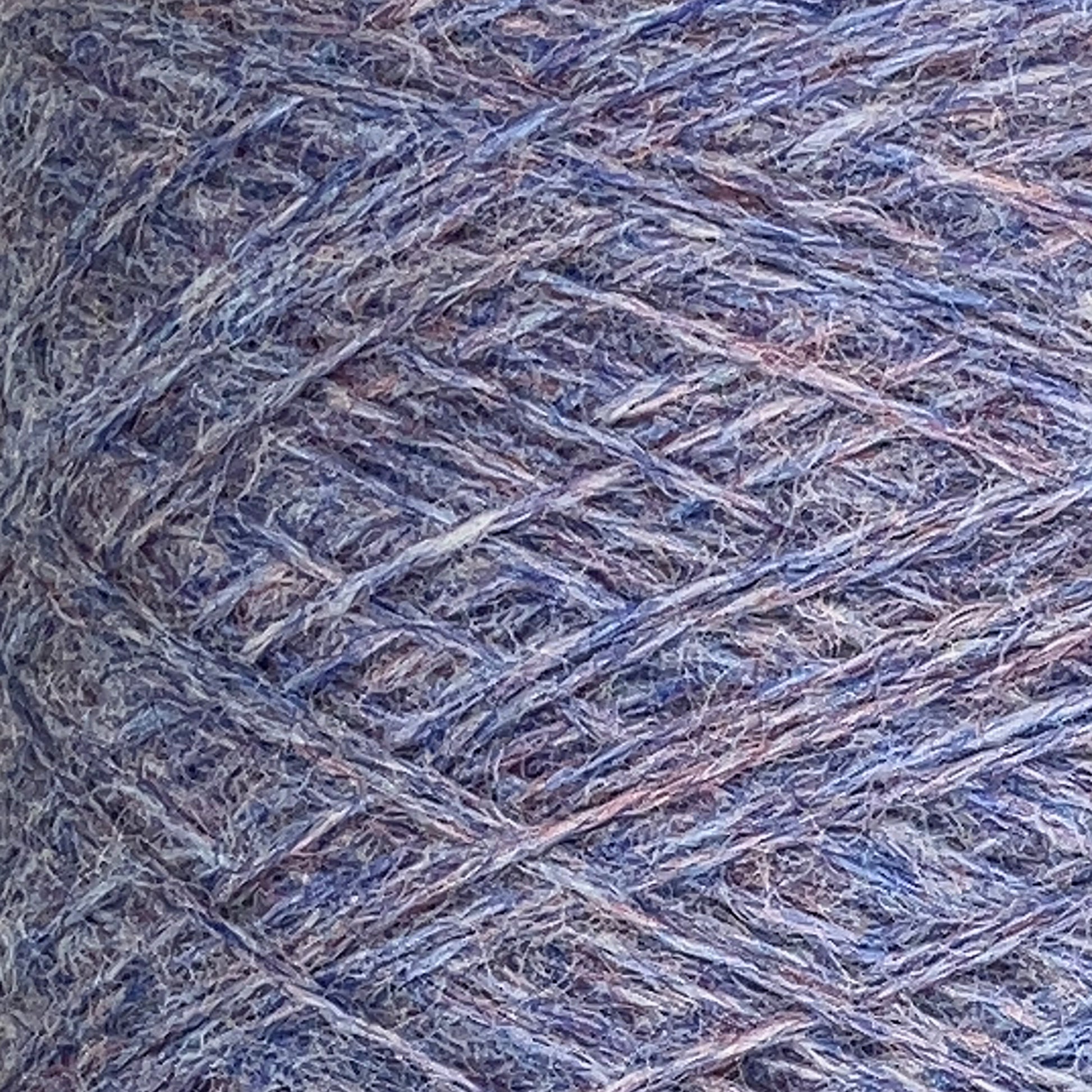 Close-up of a mini-cone of JaggerSpun Heather 2/8 yarn by Jagger Brothers, Inc., featuring a mix of purple, blue, and gray fibers. The texture is coarse and tightly wound, revealing intricate details of the interwoven strands. The softly blended colors create an overall muted pastel effect.