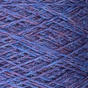 Close-up shot of textured *JaggerSpun Heather 2/8 Large Cone* yarns by *Jagger Brothers, Inc.* in shades of blue and purple, intricately interwoven. The surface displays a crisscross pattern, revealing the fine details and subtle color variations in the worsted spun strands.