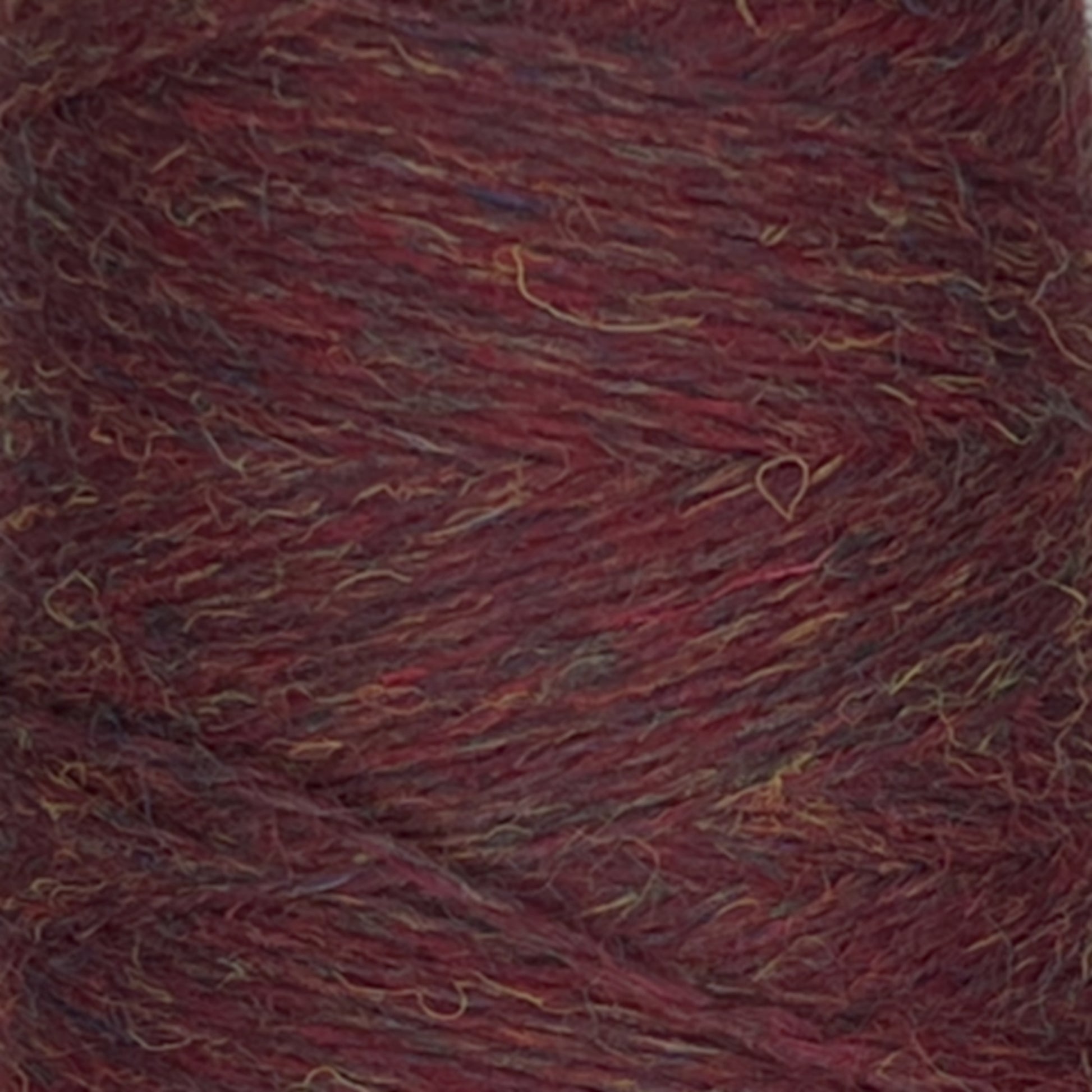 Close-up of a mini-cone of JaggerSpun Heather 2/8 yarn from Jagger Brothers, Inc., showcasing a blend of dark red, brown, and subtle hints of blue and yellow. The worsted spun wool has a slightly coarse texture with a heathered appearance, where individual fibers are visible.