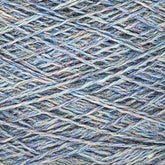 Close-up view of blue and green multicolored JaggerSpun Heather 2/8 yarns from Jagger Brothers, Inc., showcasing a complex pattern of crisscrossing fibers weaving together in varying shades. The intricate, soft texture highlights the details of this fingering gauge wool on a large cone.