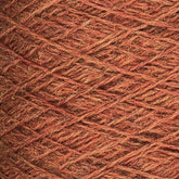 Close-up image of a ball of JaggerSpun Heather 2/8 | Mini-cone worsted spun wool by Jagger Brothers, Inc., showcasing a mix of reddish-brown tones. The yarn fibers are wound tightly in an overlapping crisscross pattern, displaying the texture and coloration achieved with low-impact synthetic dyes.