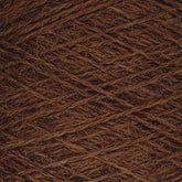 A close-up image of a ball of Jagger Brothers, Inc.'s JaggerSpun Heather 2/8 Mini-cone yarn features tightly wound threads in various shades of brown. The rough and slightly fuzzy texture indicates it is composed of natural fibers and dyed with low-impact synthetic dyes. The crisscross pattern gives an intricate view of overlapping strands.