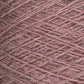 Close-up of a mini-cone spool of Jagger Brothers, Inc. JaggerSpun Heather 2/8 yarns in pink. The finely textured and densely wound yarn features various shades of pink, creating a pattern of intersecting lines and fibers. The image captures the intricate details, showcasing the use of low-impact synthetic dyes.