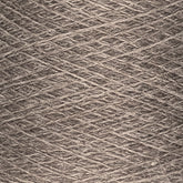 Close-up image of a ball of JaggerSpun Heather 2/8 | Mini-cone yarn from Jagger Brothers, Inc., with visible strands tightly wound together. The texture and individual fibers are clearly visible, showcasing the material. The yarn, dyed with low-impact synthetic dyes, features a neutral, natural tone.