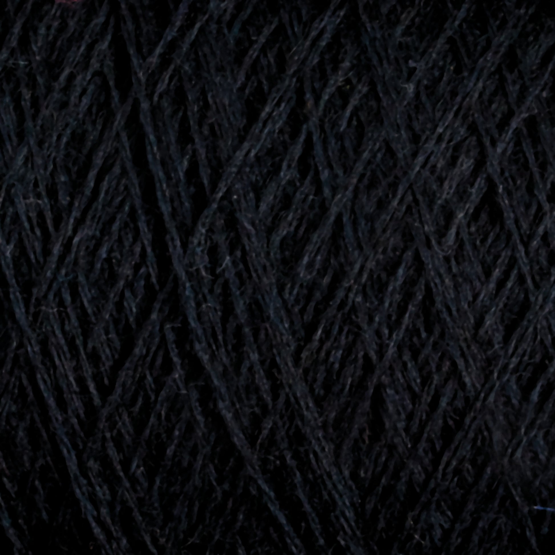 Close-up image of tightly wound dark grey JaggerSpun Superfine Merino 2/18 Yarn | Mini-cone by Jagger Brothers, Inc., featuring a soft texture and forming a dense, crisscross pattern. The fibers appear smooth and slightly fuzzy, with a subtle color gradient ranging from deep charcoal to lighter grey tones—ideal for hand knitters' projects.