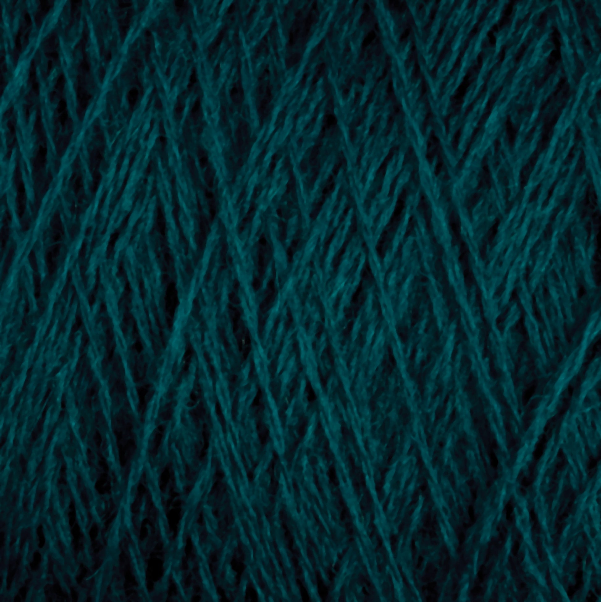 A close-up view of JaggerSpun Superfine Merino 2/18 Yarn in teal from Jagger Brothers, Inc. reveals intertwined fibers creating a detailed, crisscross pattern. The yarn appears thick and soft, perfect for knitting or crocheting.